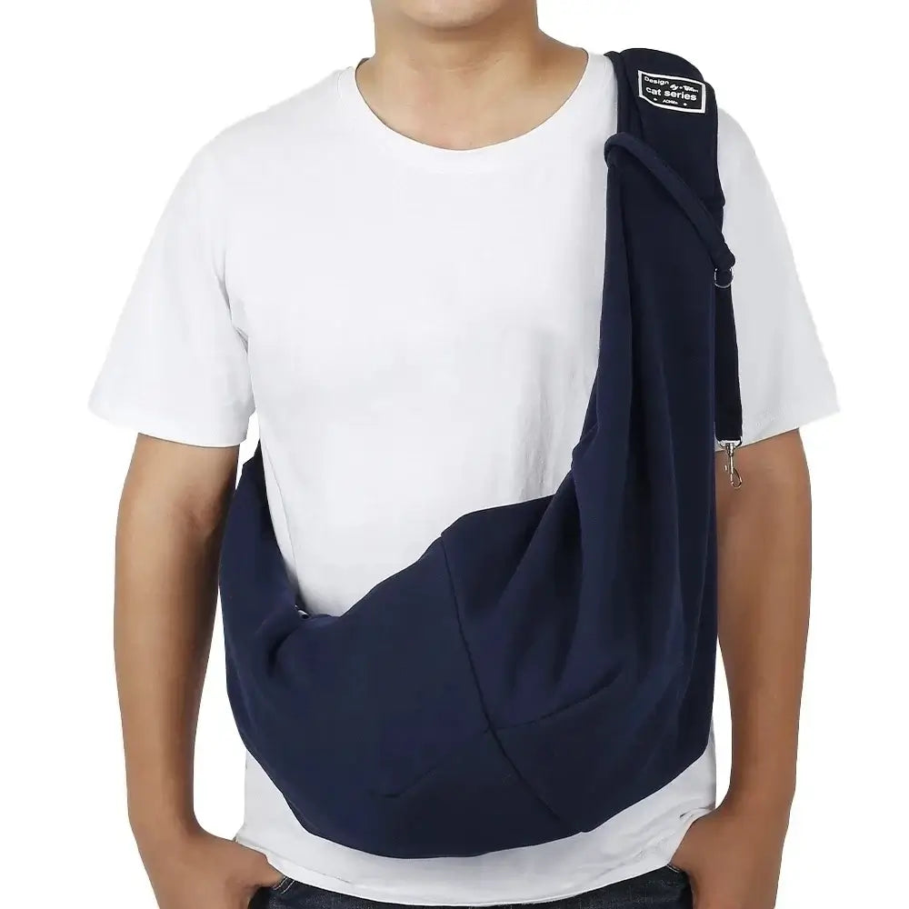 Man wearing a navy blue cotton pet carrier sling with adjustable shoulder strap and phone pocket, ideal for outdoor travel and pets up to 6.5kg.