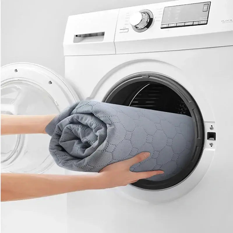 Dog cooling mat being placed into washing machine for cleaning. Quilted, washable, reusable design ensures convenience and hygiene.