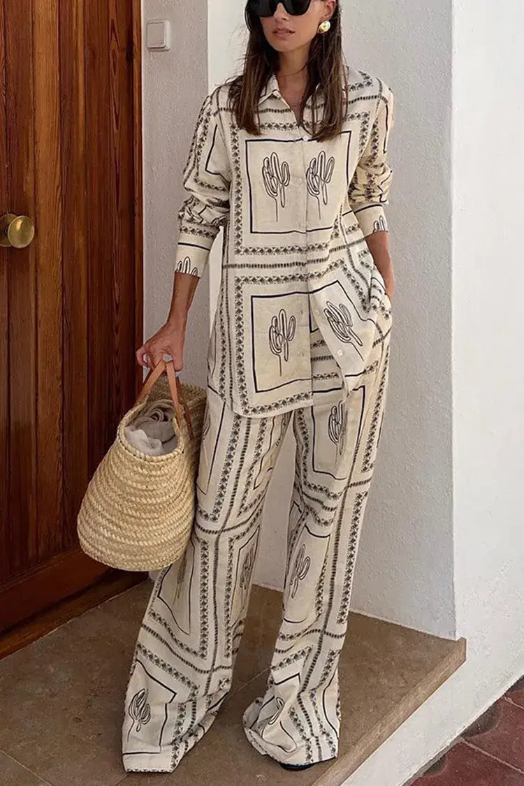 Stylish woman in a long sleeve printed lapel shirt and high waist wide leg pants set, holding a straw bag.
