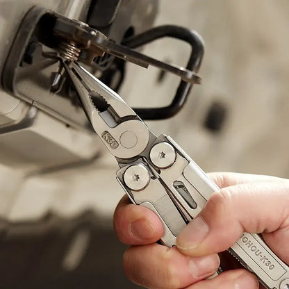 Close-up of a hand using a multitool folding knife for precise gripping and repair tasks on machinery.