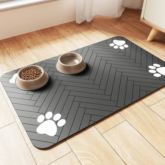 Pet feeding mat with rubber backing featuring a sleek design and paw prints, holding food and water bowls on a wooden floor.